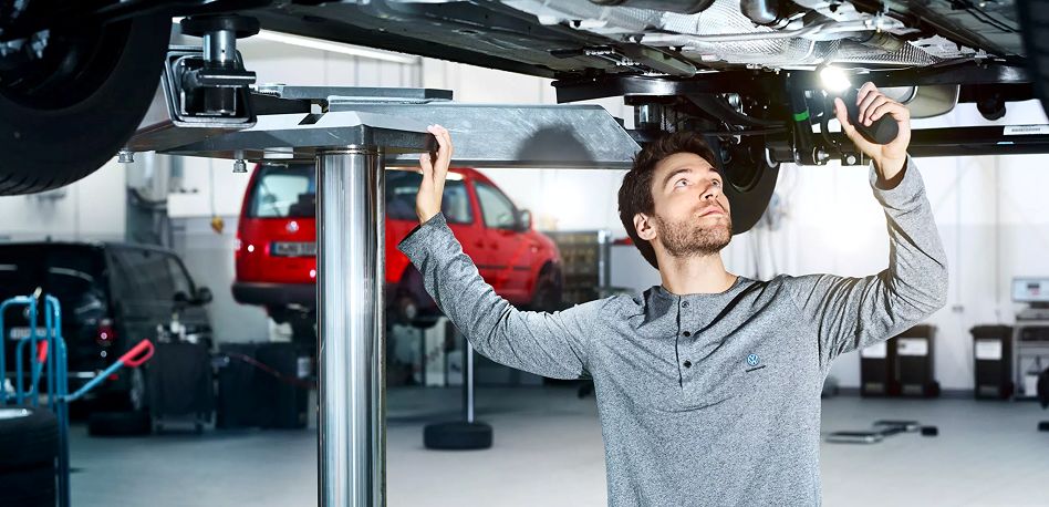 Técnico Volkswagen inspecionando um carro na oficina